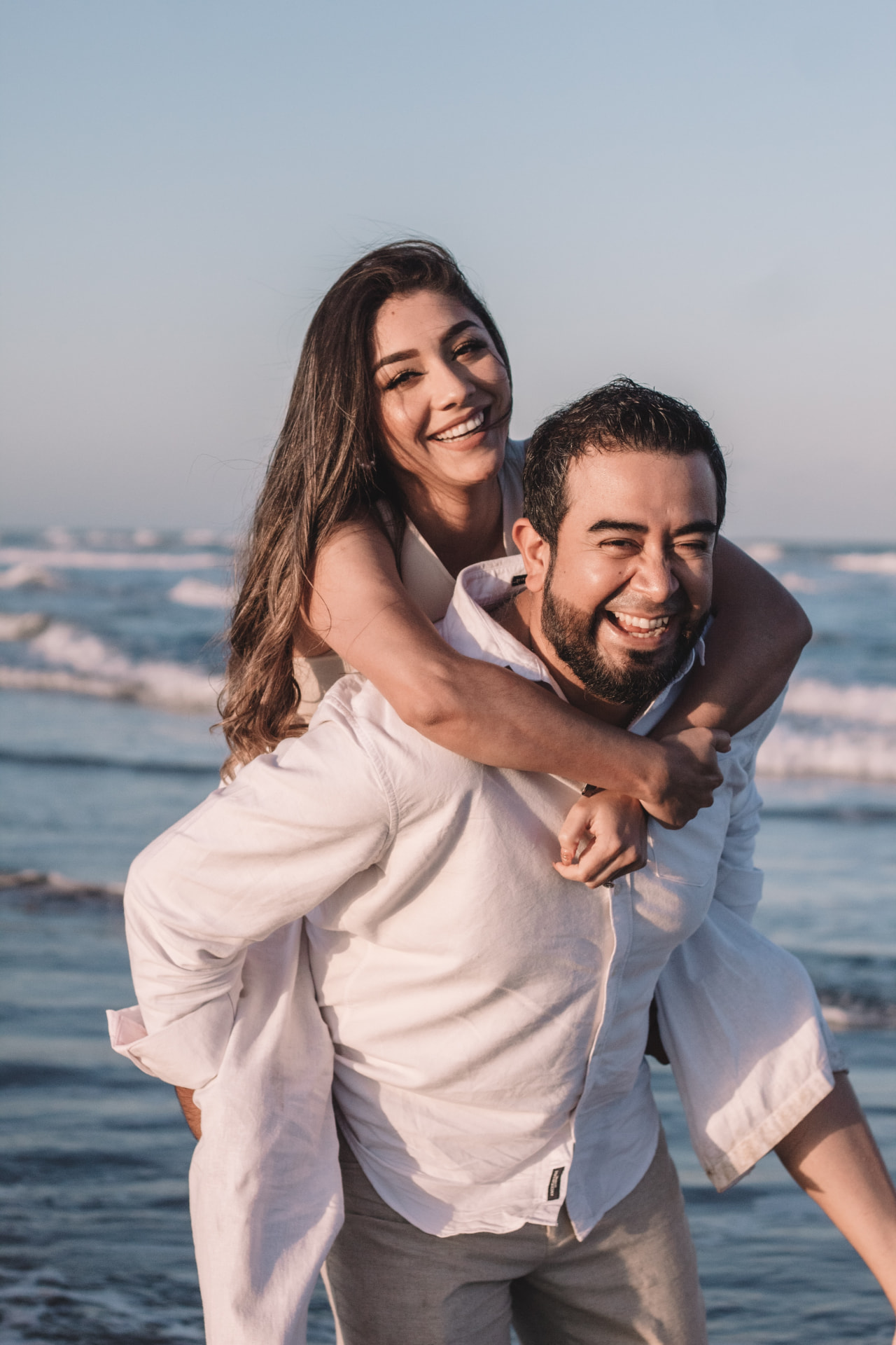A playful couple laughing together at the beach